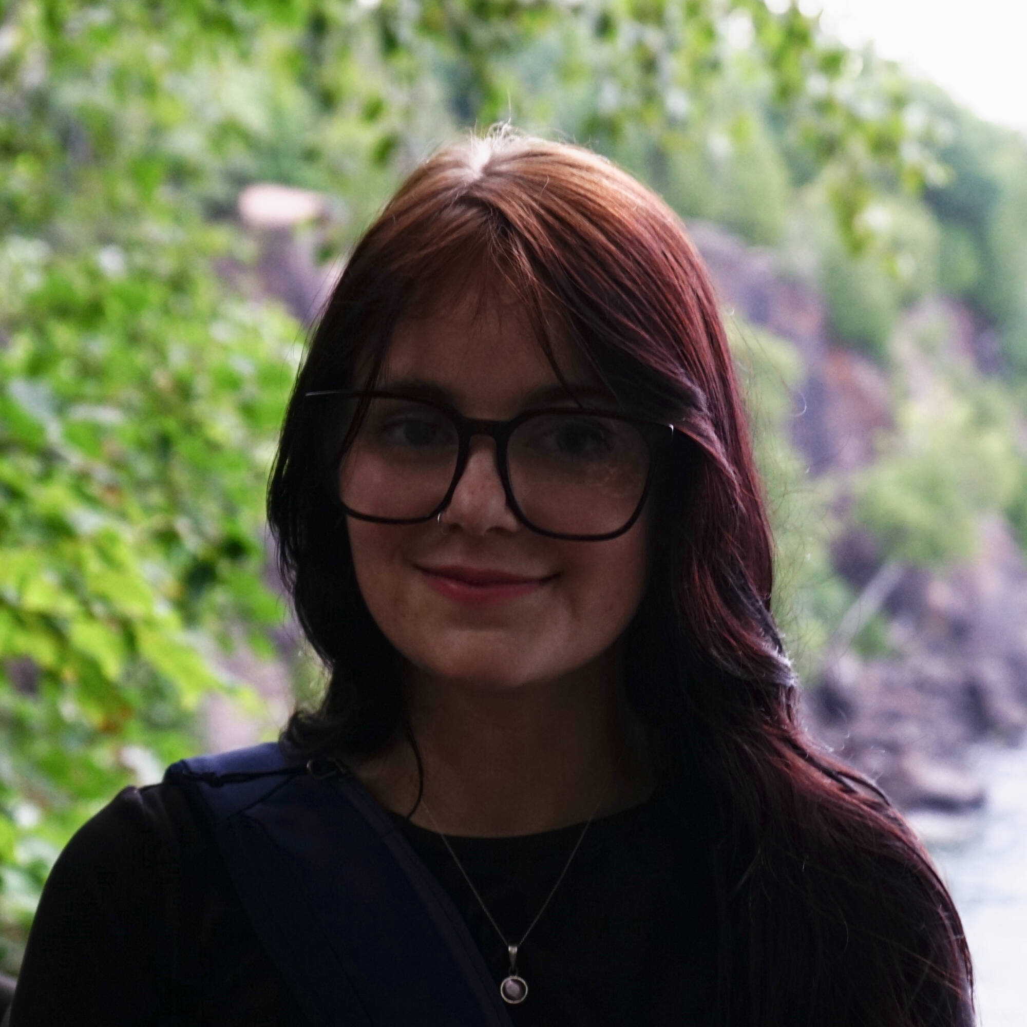 Image of smiling young woman in foreground and coastline in background